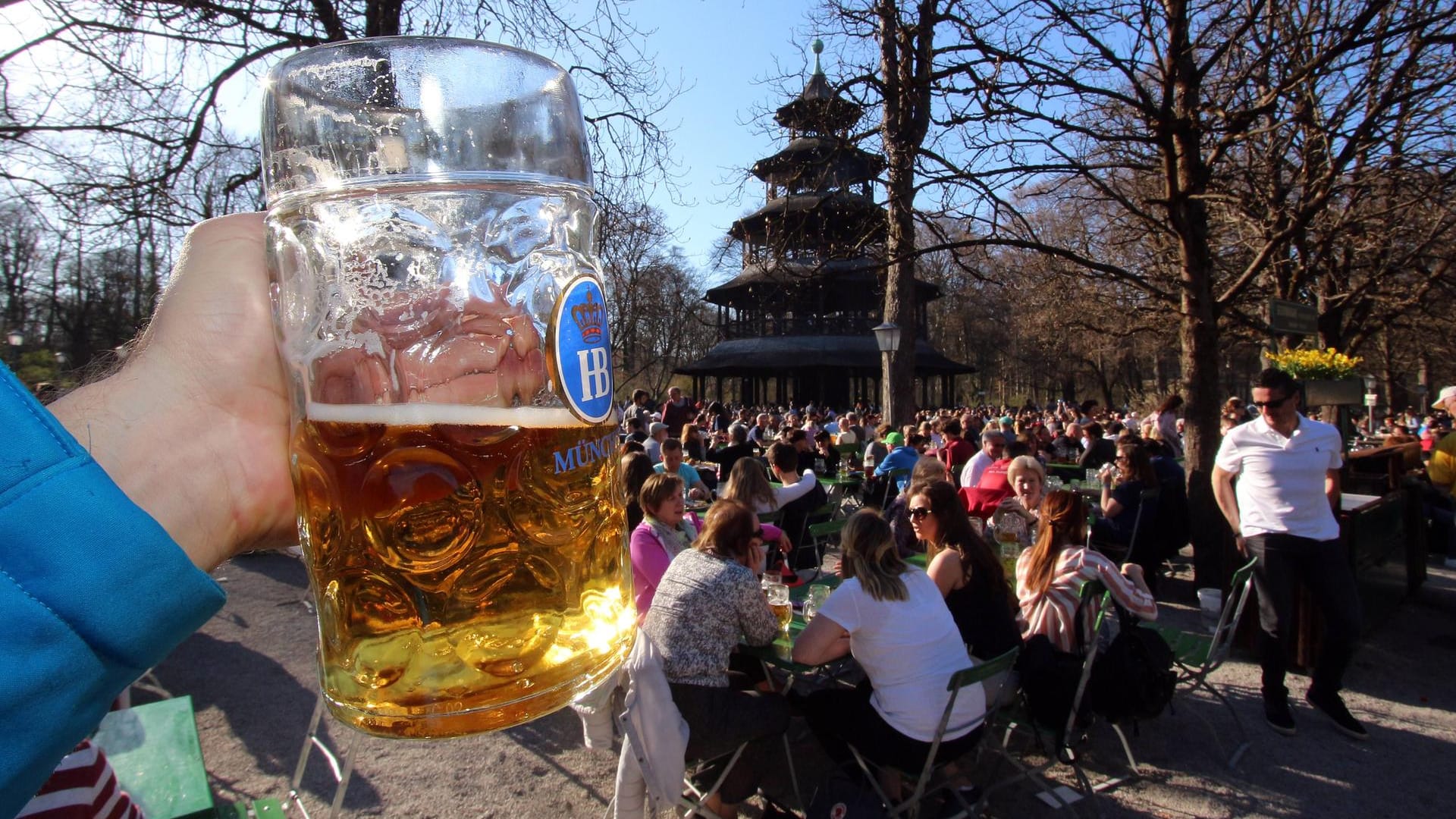 Hand mit Maß Bier im voll besetzten Biergarten am Chinesischen Turm Hand mit Maß Bier im voll besetzten Biergarten am Chinesischen Turm