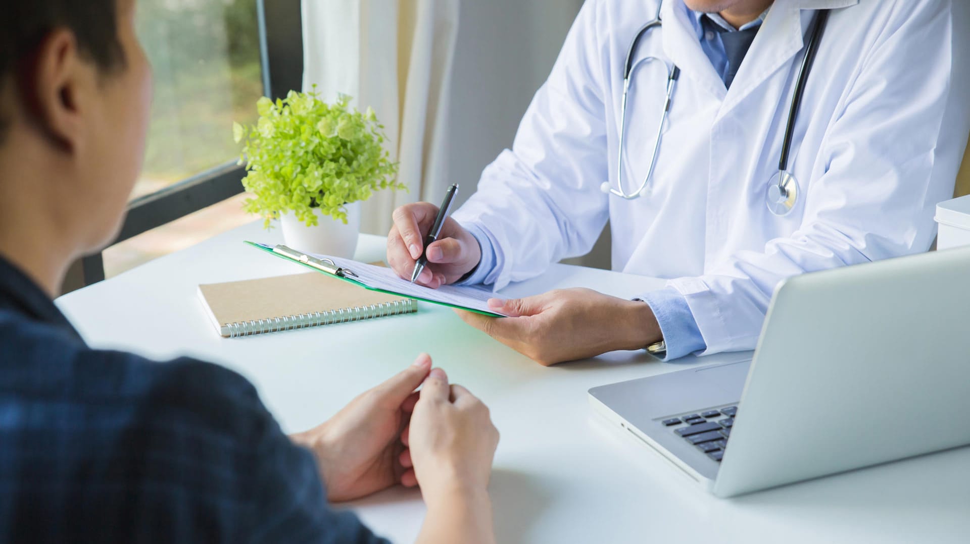 Arzt macht sich im Gespräch mit einem Patienten Notizen Arzt macht sich im Gespräch mit einem Patienten Notizen