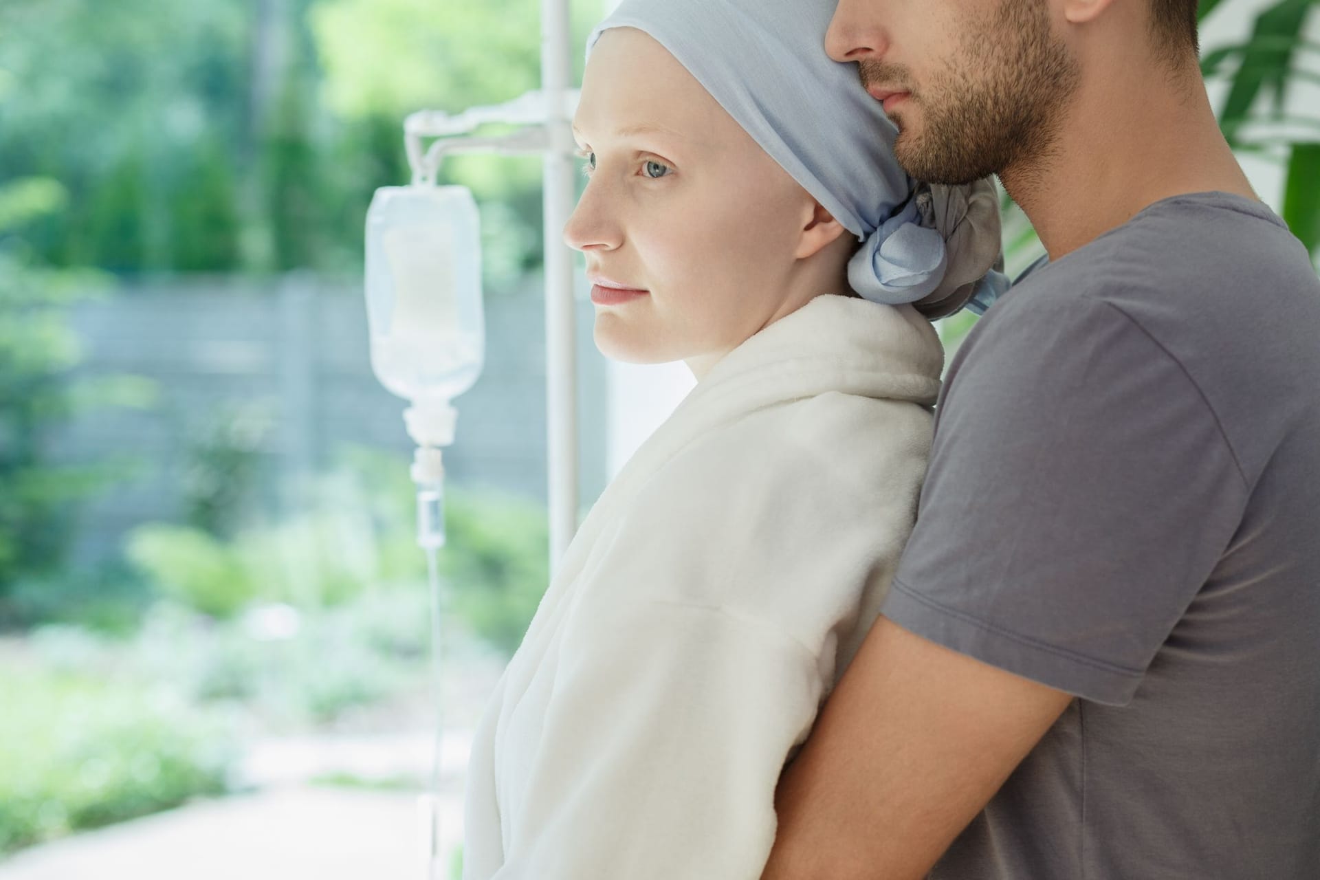 An Krebs erkrankte junge Frau wird von ihrem Mann umarmt An Krebs erkrankte junge Frau wird von ihrem Mann umarmt