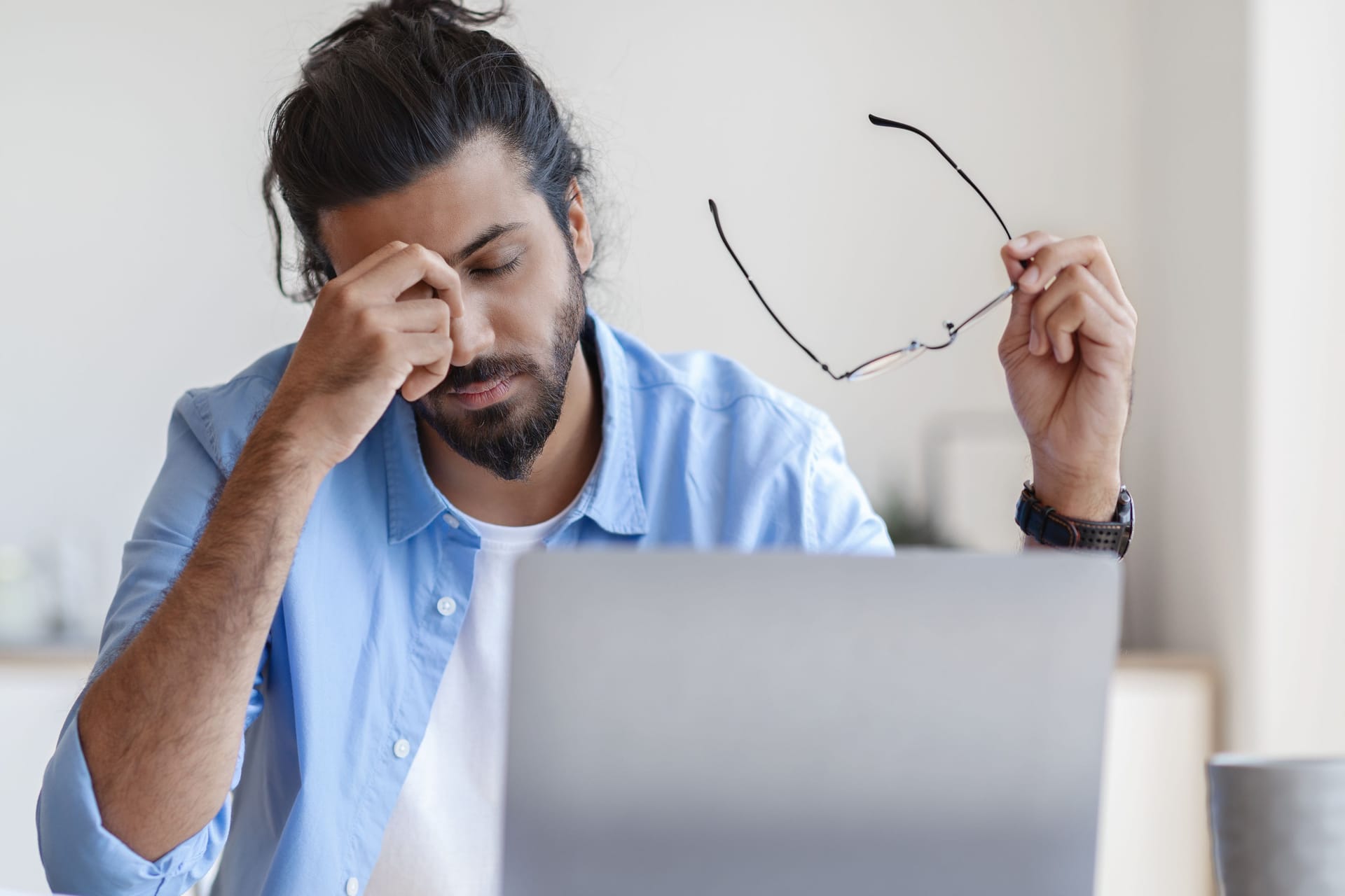 Müder Mann sitzt vor einem Laptop