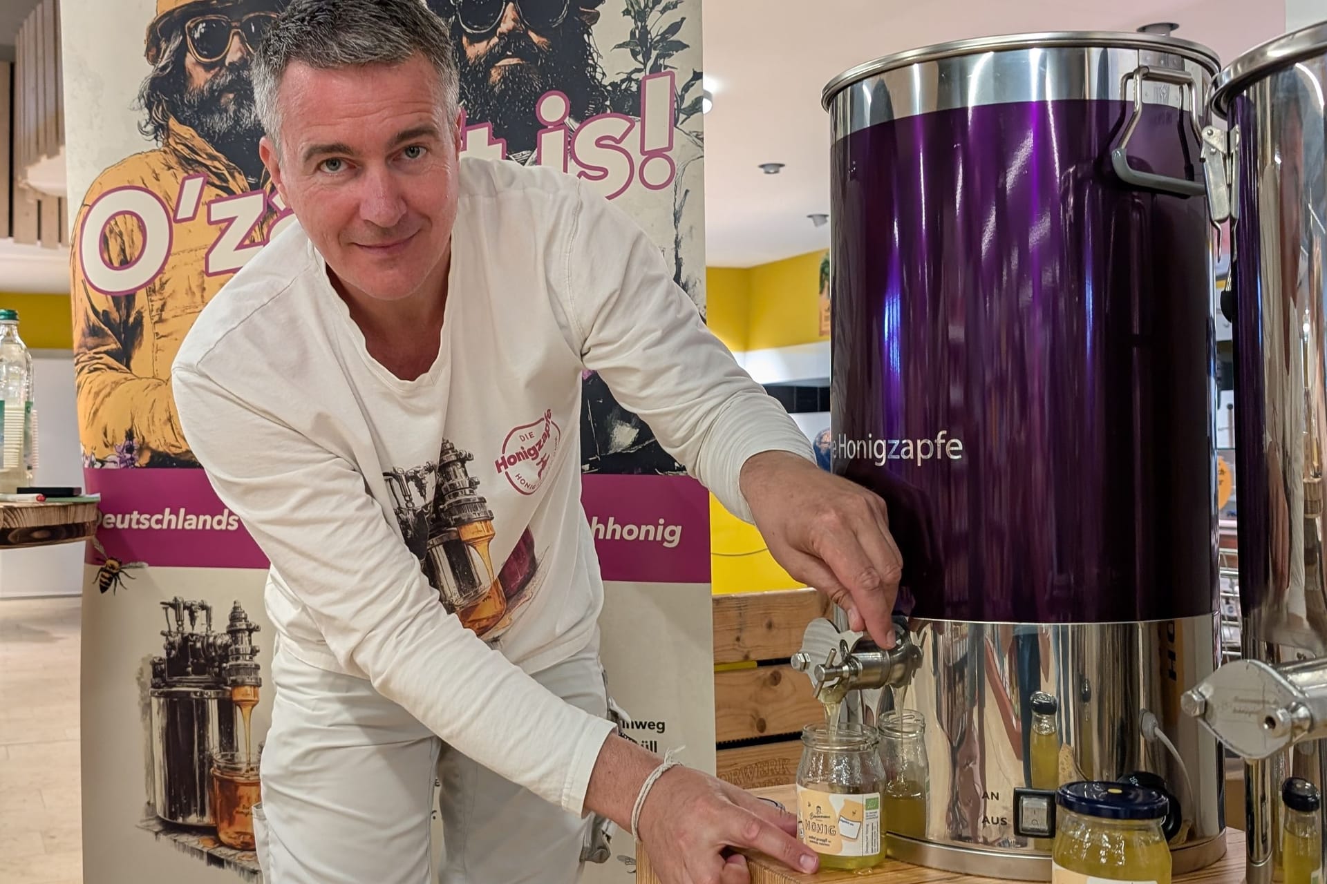 Imker Rico Heinzig zampft sich ein Glas Honig: Seit Dienstag steht die Anlage im Biomarkt in Coswig.